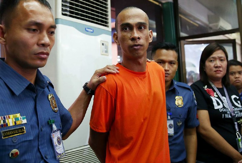 Authorities escort Anselmo Ico, suspected of participating in a child-porn ring, after he was presented to the media Friday in Manila, Philippines.