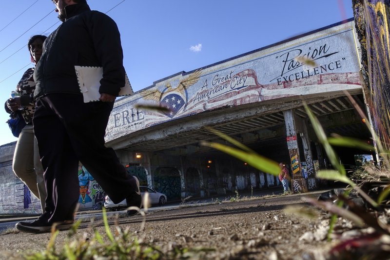 In this Oct. 24, 2017, photo, pedestrians pass under a freight train overpass as they walk up Peach Street in Erie, Pa. Since 2008, Erie has suffered a hidden and potentially more devastating exodus: The loss of well-paid white-collar jobs. Half its CEOs have disappeared. The city has shed 8 percent of its accountants, 10 percent of its computer workers, 40 percent of its engineers and 20 percent of its lawyers, according to government occupational data analyzed by The Associated Press. (AP Photo/John Minchillo)