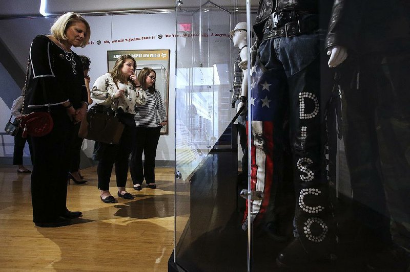 Visitors Katy Nelson (left) of Fayetteville, Catherine Campos (center) of Miami, and Mollie May Henager of Little Rock check out the disco display that’s part of the “Louder than Words: Rock, Power and Politics” exhibit before former President Bill Clinton’s talk at the Clinton Presidential Center on Sunday in Little Rock.