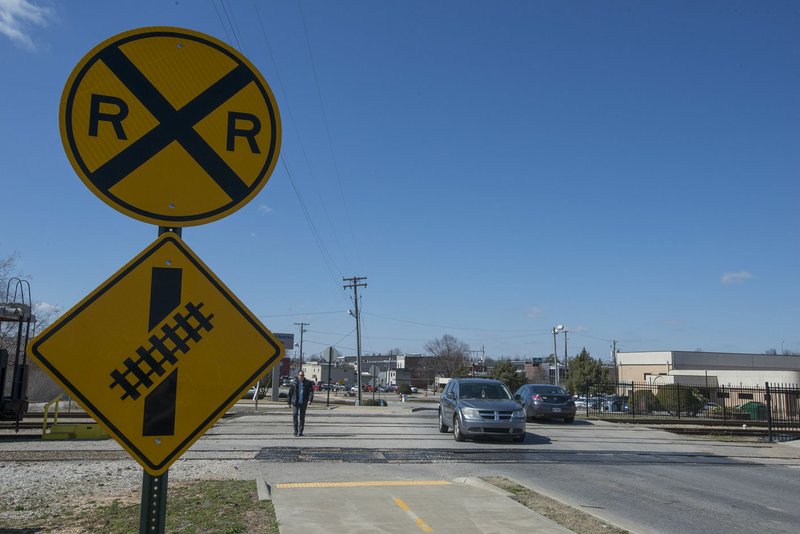 NWA Democrat-Gazette/J.T. WAMPLER A vehicle and a pedestrian cross the railroad tracks on Meadow Street Wednesday in Springdale. The city is considering closing the crossing which is just south of the train depot on Emma Avenue.