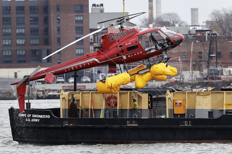 The Associated Press HELICOPTER HOISTED: A helicopter is hoisted by crane from the East River onto a barge, Monday in New York. The pilot was able to escape the Sunday night crash after the aircraft flipped upside down in the water killing several passengers, officials said.