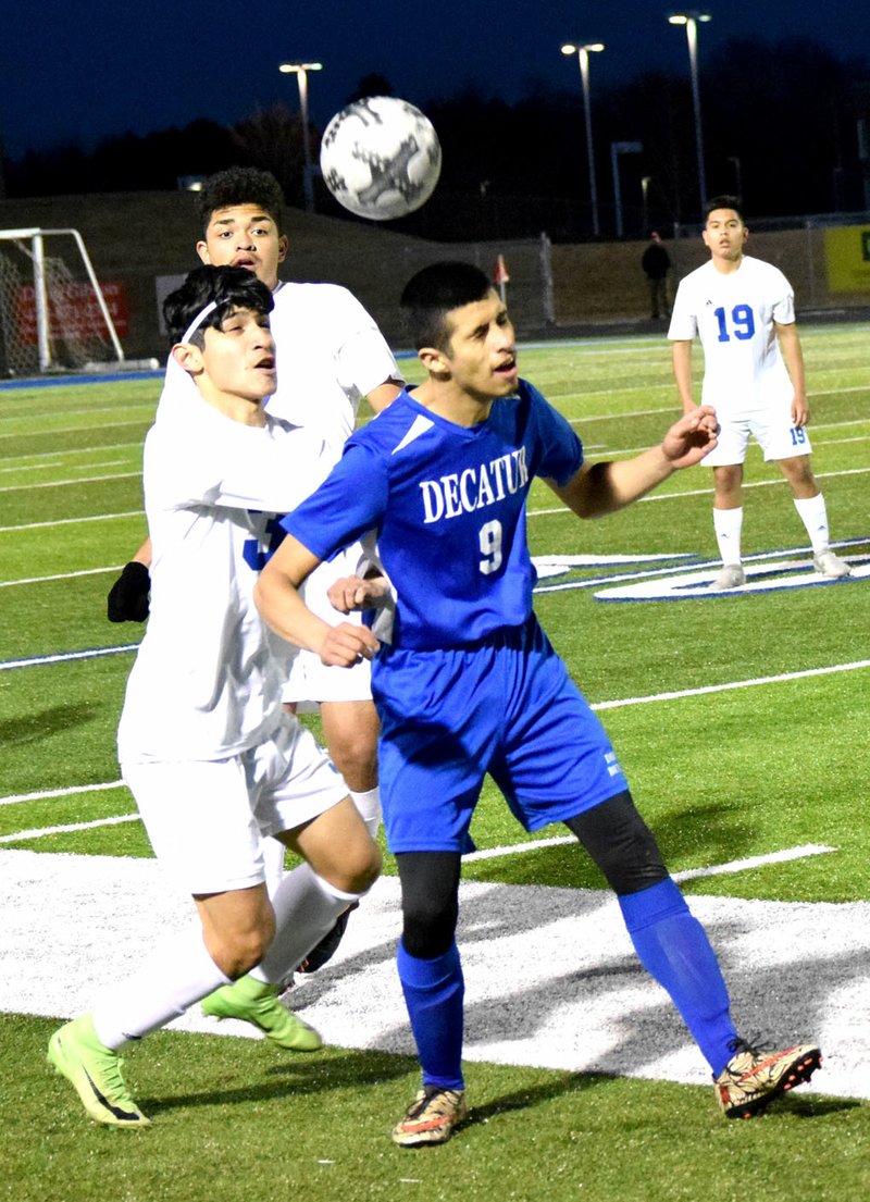 Westside Eagle Observer/MIKE ECKELS Jimmy Mendoza (Decatur 9) uses his head to deflect the ball away from a pair of Mountie players in the second half of the Rogers-Decatur boys' soccer match at Mountie Stadium in Rogers March 8.