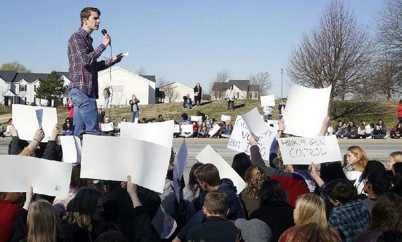 NWA Democrat-Gazette/DAVID GOTTSCHALK  Andrew Van Slooten, a senior at Bentonville High School and member of the Bentonville High School Students for Safer Schools, reads Wednesday, March 14, 2018, the names and a brief biography of the 17 shooting victims at Marjory Stoneman Douglas High School in Parkland, Florida, during a 17 minute silent observance. About 400 students from the school participated in the silence and a series of chants and speeches as they lined S.E. J Street in Bentonville.