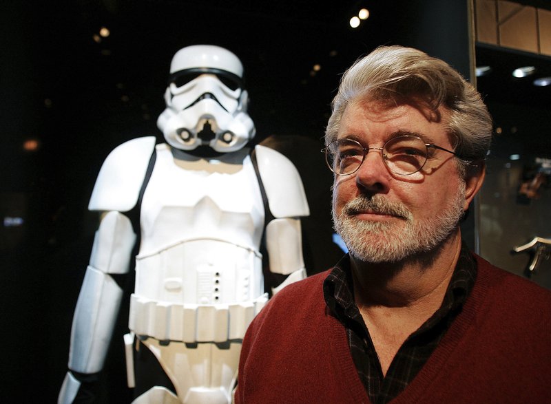 FILE - In this Oct. 22, 2005 file photo, filmmaker George Lucas poses in front of a Stormtrooper exhibit at the Museum of Science in Boston, prior to the opening of "Star Wars: Where Science Meets Imagination." Lucas is visiting a galaxy on the edge of downtown Los Angeles to break ground on his $1.5 billion Lucas Museum of Narrative Art. The "Star Wars" creator and his wife will be joined Wednesday morning, March 14, 2018, by several city and county officials to ceremoniously begin work on turning a section of Exposition Park into the new museum. (AP Photo/Winslow Townson, File)