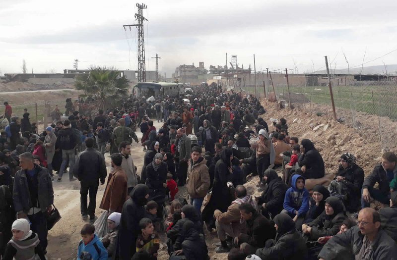 This photo released by the Syrian official news agency SANA, shows Syrian civilians with their belongings, fleeing fighting between Syrian government forces and rebels, in eastern Ghouta, a suburb of Damascus, Syria, Thursday, March. 15, 2018. Thousands of civilians streamed out of Hamouria in Syria's besieged, opposition-held enclave of eastern Ghouta on Thursday, crossing on foot and in pick-up trucks and tractors to government-held territory near the capital, Damascus, according to footage on state-run Syrian television. (SANA via AP)
