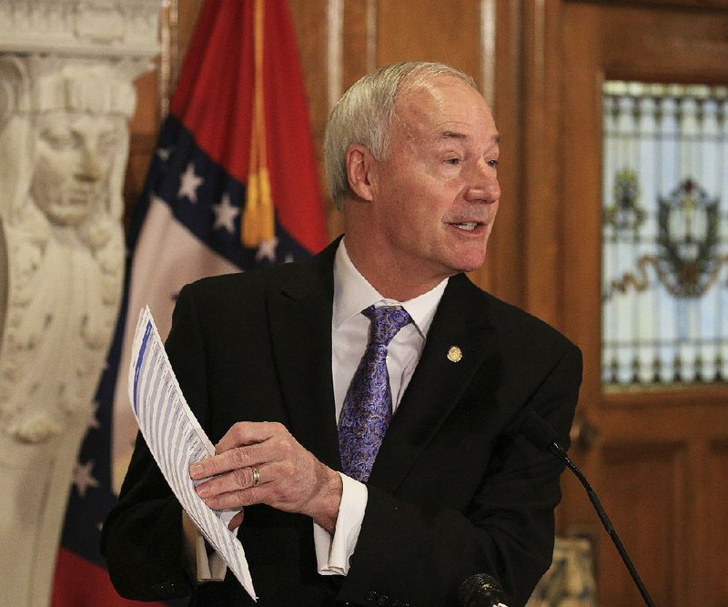 Gov. Asa Hutchinson talks  to  reporters Thursday at  the Capitol about his plan to reduce the number of state agencies that report to his office. He said  the plan would be considered  in  the 2019 regular legislative session.
