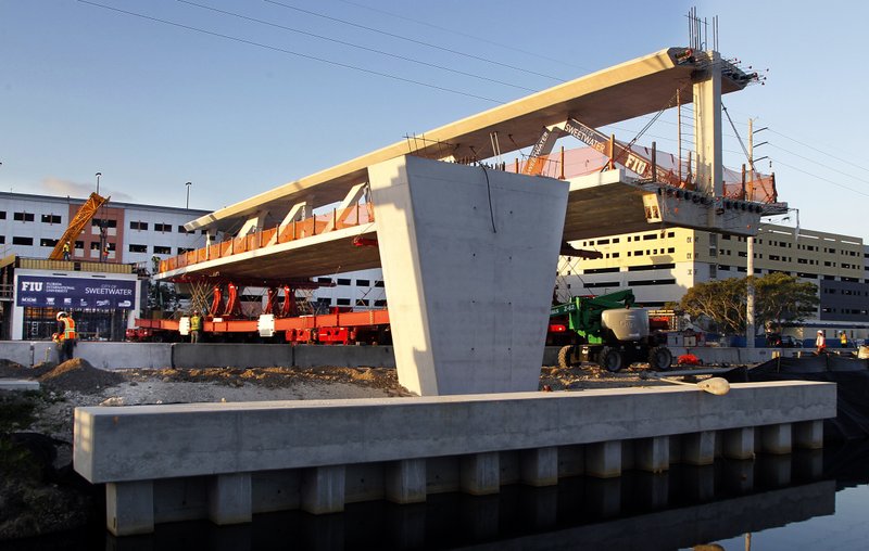 this March 10, 2018 photo shows an early morning view of the main span of the a pedestrian bridge that is being positioned to connect the City of Sweetwater, Fla., to Florida International University near Miami. The 950- ton new bridge collapsed, Thursday, March 15, over several cars causing several fatalities and injuries. (Pedro Portal/ The Miami Herald via AP)