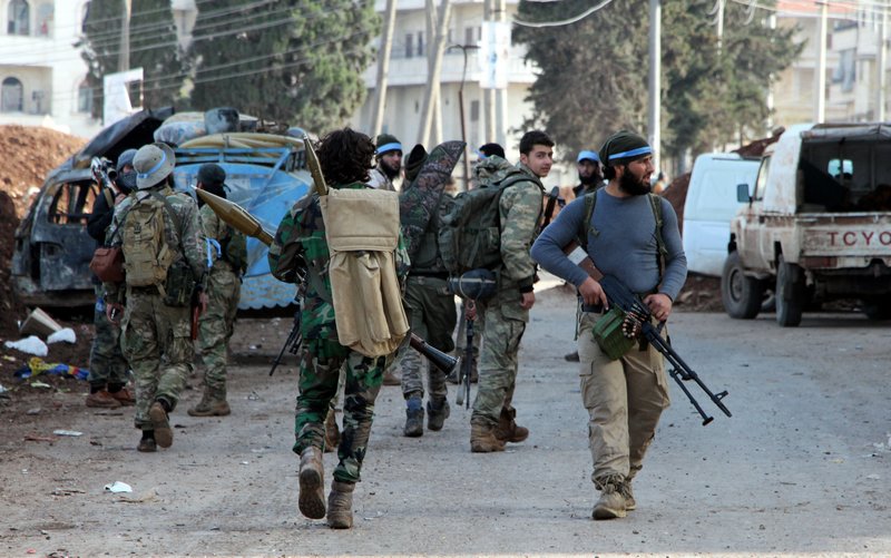 Turkey-backed Free Syrian Army soldiers walk in the city center of Afrin, northwestern Syria, early Sunday, March 18, 2018. Turkey's President Recep Tayyip Erdogan said Sunday that allied Syrian forces have taken "total" control of the town center of Afrin, the target of a nearly two-month-old Turkish offensive against a Syrian Kurdish militia, which said fighting was still underway. Erdogan said the Turkish flag and the flag of the Syrian opposition fighters have been raised in the town, previously controlled by the Kurdish militia known as the People's Defense Units, or YPG. (Hasan Kırmızitaş/DHA-Depo Photos via AP)