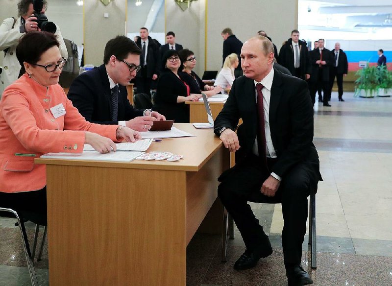 Russian President Vladimir Putin waits to receive his ballot Sunday at a polling station in Moscow.