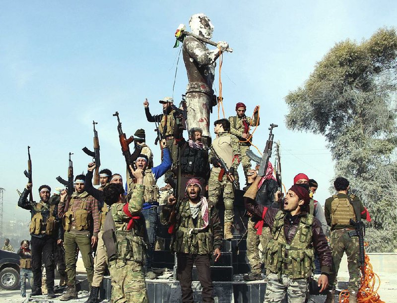 Turkey-backed Free Syrian Army soldiers celebrate around a statue of Kawa, a mythological figure in Kurdish culture, after capturing the enclave of Afrin, Syria, from the Kurds on Sunday. The soldiers planned to destroy the statue.