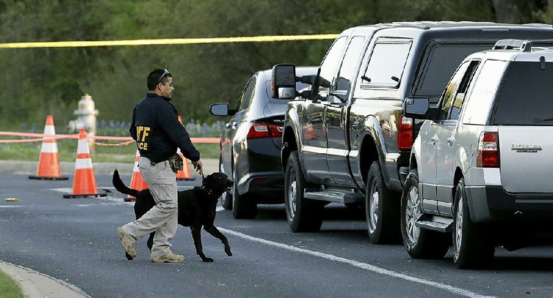 An agent with the Bureau of Alcohol, Tobacco, Firearms and Explosives works with a dog Monday near the site of Sunday’s explosion in Austin, Texas.