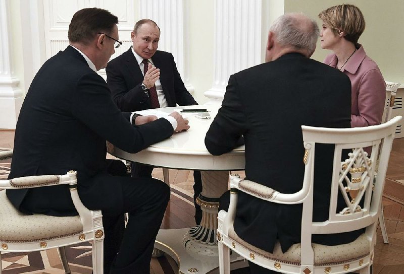 Russian President Vladimir Putin meets with campaign co-chairmen Monday at his campaign headquarters in Moscow.