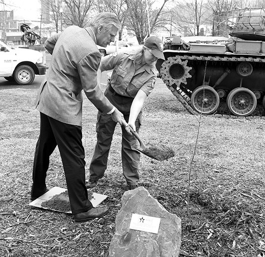 The Sentinel-Record/Richard Rasmussen DEDICATION: Hot Springs Mayor Pat McCabe, left, and Regine Skelton, a county forester and urban representative with the Arkansas Forestry Commission, toss dirt on a willow oak tree at the Garland County Veterans Memorial and Military Park on Monday during a dedication ceremony. The tree was planted to honor those who served in the military during World War I.