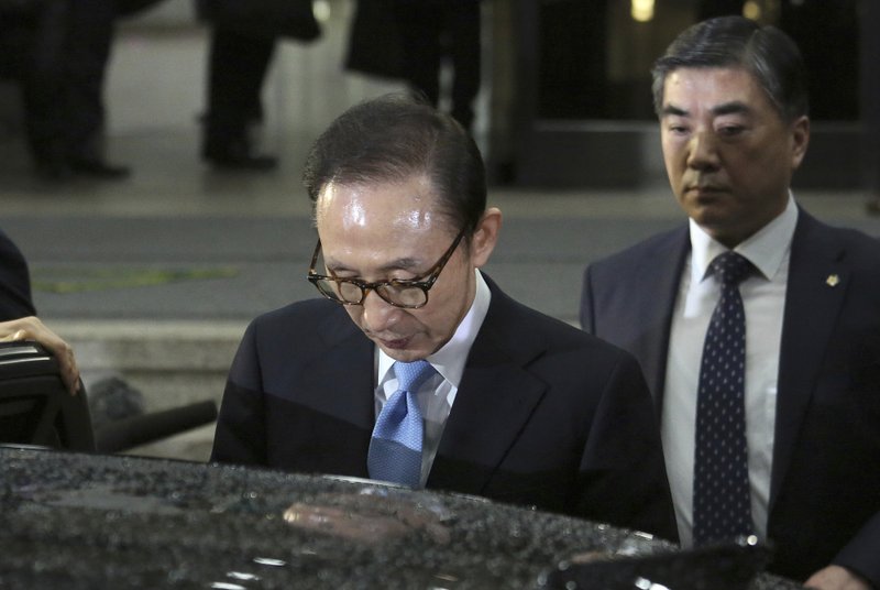In this Thursday, March 15, 2018, photo, former South Korean President Lee Myung-bak, left, gets into a car to leave the Seoul Central District Prosecutors' Office in Seoul, South Korea. South Korean prosecutors said Monday, March 19, 2018 they have requested an arrest warrant for Lee over corruption allegations. (AP Photo/Ahn Young-joon)