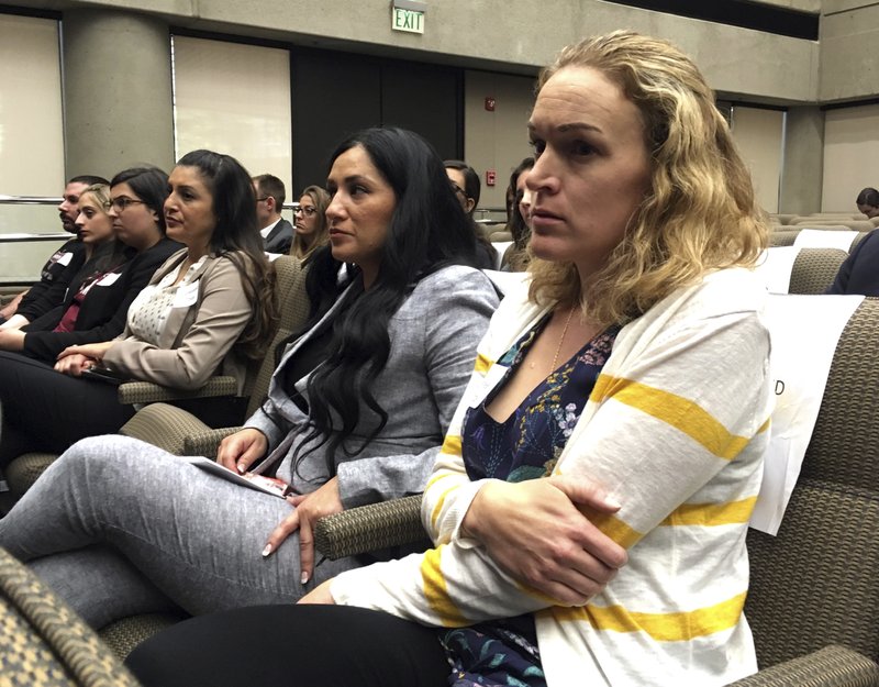 Renee Wetzel, right, whose husband died in the 2015 San Bernardino terrorist attack, watches as fellow family members of mass shooting victims call on California's public pension fund to stop investing in retailers that sell assault weapons in Sacramento, Calif., on Monday, March 19, 2018. W (AP Photo/Kathleen Ronayne)