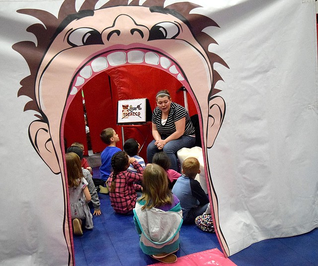 Westside Eagle Observer/MIKE ECKELS Inside a giant mouth, Allyson Carter, a teacher at Decatur Northside Elementary, shows students proper dental hygiene during the Farm and You program in the safe room at Northside March 8.