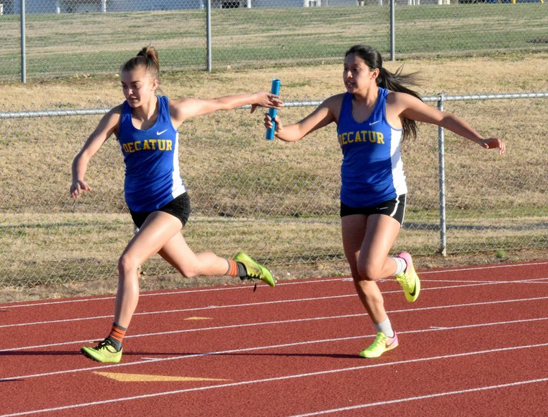 Westside Eagle Observer/MIKE ECKELS Decatur's Destiny Mejia (left) takes the hand-off from Heidi Rubi during the final leg of the girls' 4x100 meter relay of the Tiger Invitational Track Meet at Bentonville High School stadium March 16. Mejia and Rubi, along with Paige Vann and Stephanie Sandoval, took second place in the event.