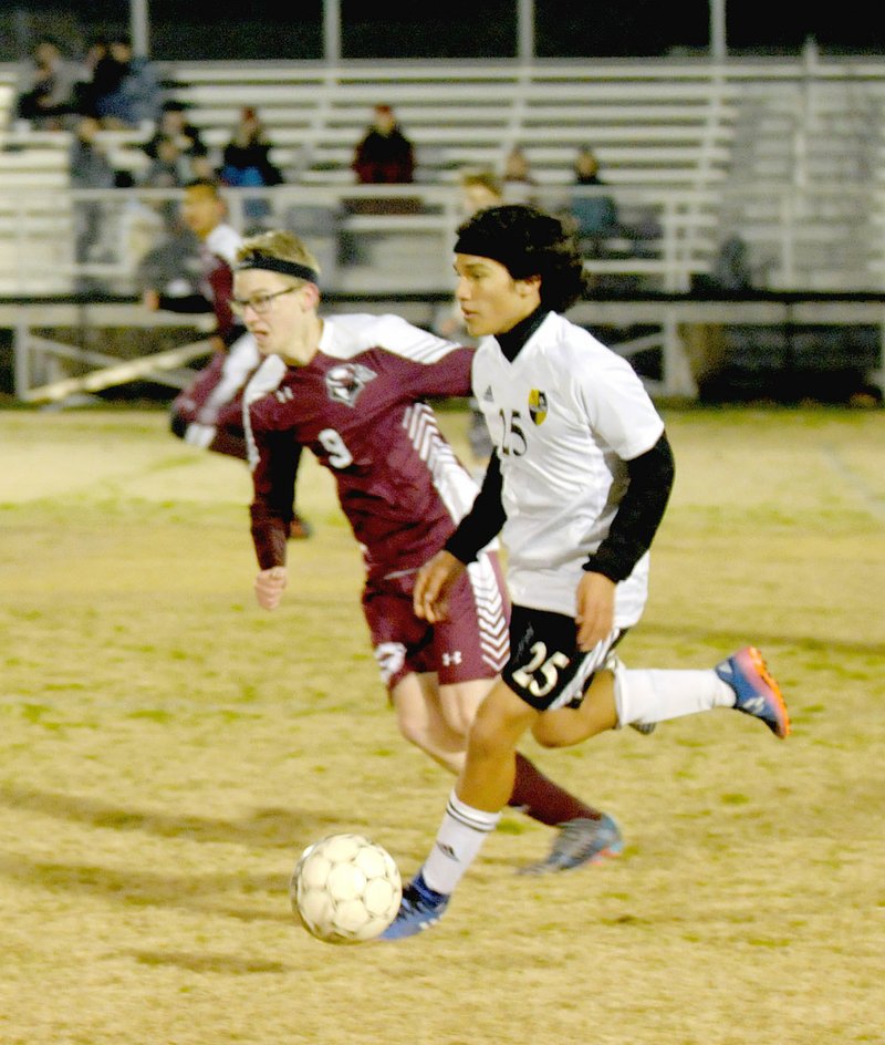 MARK HUMPHREY ENTERPRISE-LEADER Prairie Grove sophomore Francisco Estrada moves the ball downfield with Gentry sophomore Ben Nelson in pursuit during boys soccer action on Monday, March 12, at Prairie Grove. The Tigers defeated the Pioneers 3-0.