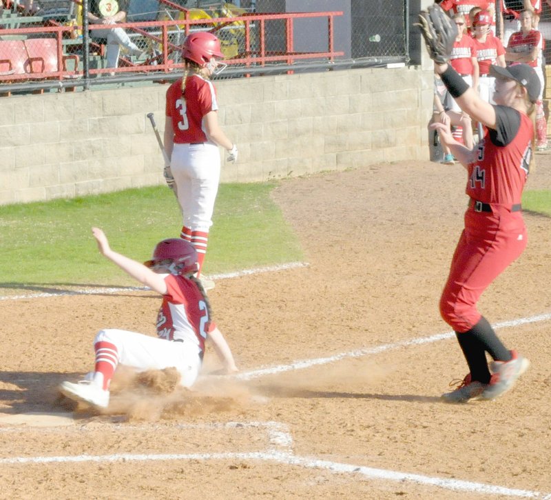 MARK HUMPHREY ENTERPRISE-LEADER Farmington sophomore Paige Anderson slides home to score a run on a passed ball while Mena pitcher Autumn Powell tries to cover home plate. The Lady Cardinals prevailed 12-0 and placed second in the Farmington Invitational softball tournament they hosted last weekend.