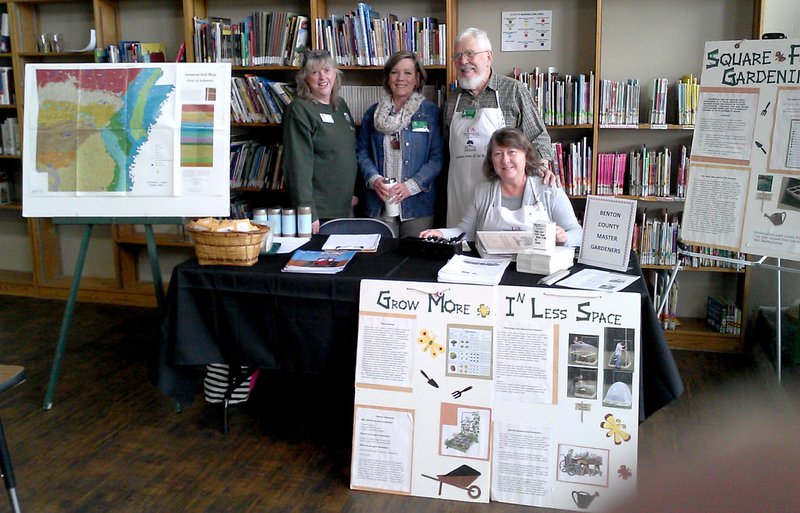 Photo by Karen Benson Benton County Master Gardeners Phyllis Stair, Vicki Halley, Burt Crume and Linda Crume pose at their booth at the Gravette Public Library seed swap. They displayed colorful posters with gardening information, distributed French marigold seeds and literature on gardening and answered many gardeners' questions.