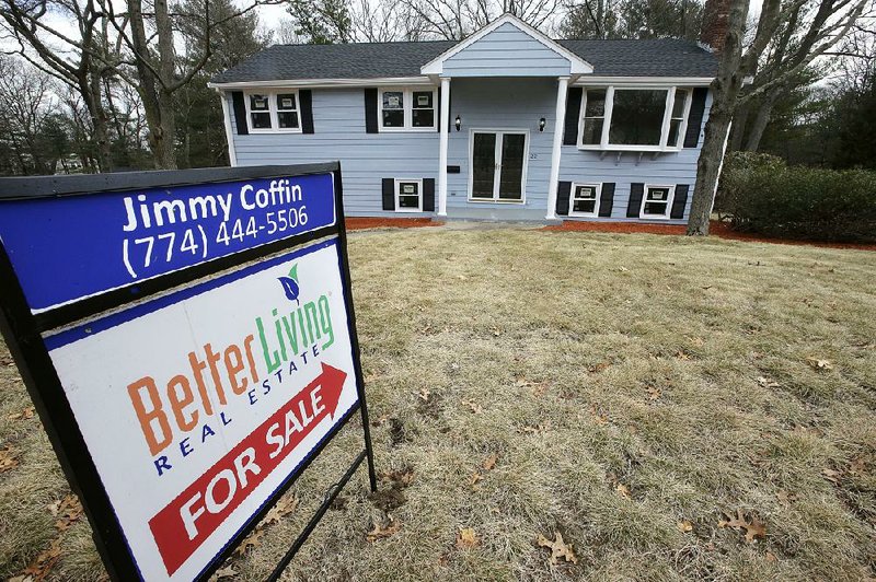 A sign stands in front of a house in Walpole, Mass., last month. Sales of existing U.S. homes rose in February, the National Association of Realtors said Wednesday.  