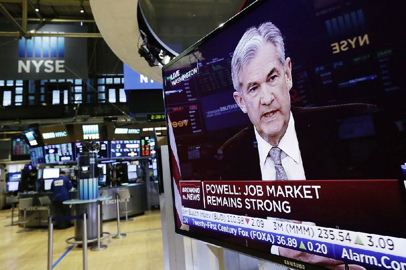 Federal Reserve Chairman Jerome Powell’s news conference in Washington appears on a television Wednesday on the floor of the New York Stock Exchange after the Fed raised its benchmark interest rate to reflect a solid U.S. economy.  