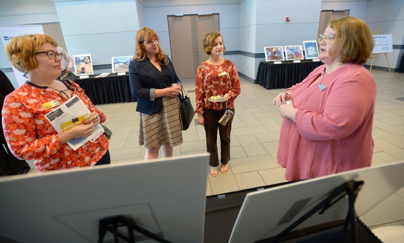 NWA Democrat-Gazette/ANDY SHUPE Kelly Colebar (from right), community resources administrator for Fayetteville's Community Resources Division, speaks Wednesday about the city's Hearth Program with Andrea Newby, Rachel Reynolds and Erika Wilhite, all representatives of Artist's Laboratory Theatre, during a Community Development Block Grant fair at Fayetteville Town Center. The Hearth Program offers housing assistance and is one of several city-sponsored programs explained at the fair.