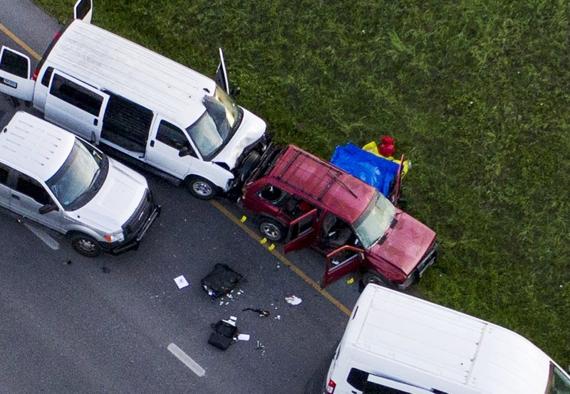 Officials investigate near a vehicle, center, where a suspect in the deadly bombings that terrorized Austin blew himself up as authorities closed in on him, in Round Rock, Texas, Wednesday, March 21, 2018. (Jay Janner/Austin American-Statesman via AP)