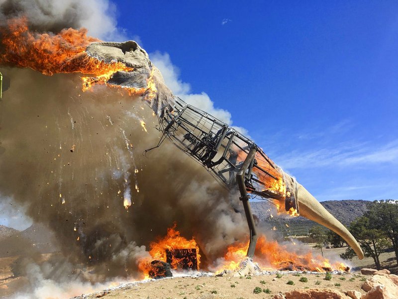 In a Thursday, March 22, 2018, photo provided by the Royal Gorge Dinosaur Experience, a life-sized animatronic Tyrannosaurus Rex at the Royal Gorge Dinosaur Experience in Canon City, Colo., is ablaze after an electrical issue, according to Royal Gorge Dinosaur Experience personnel. 