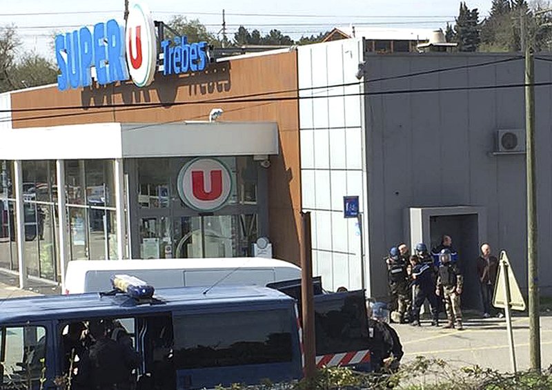 In this image provided by Newsflare/Tarbouriech Roseline police gather outside a supermarket in Trebes, southern France, Friday March 23, 2018. An armed man took hostages in a supermarket in southern France on Friday, killing two and injuring about a dozen others, police said. He had earlier opened fire on officers nearby.
