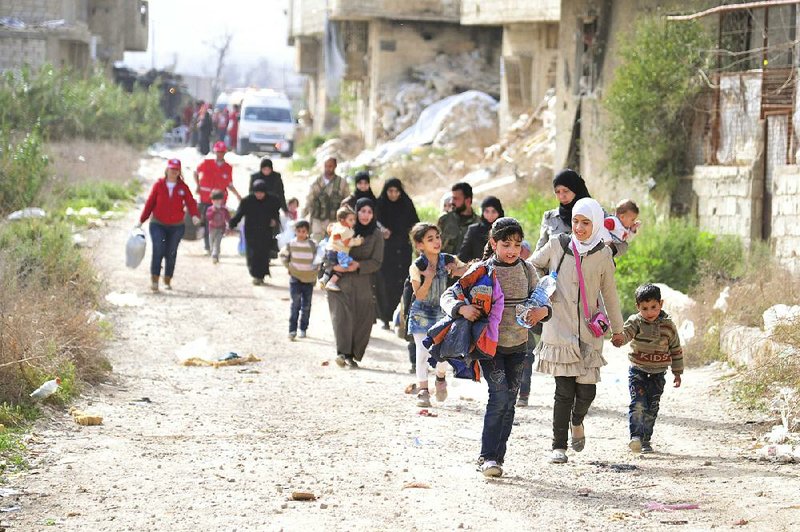 Civilians in Syria flee from fighting between Syrian government forces and insurgents through the Wafideen crossing Thursday in eastern Ghouta, a suburb of Damascus. 