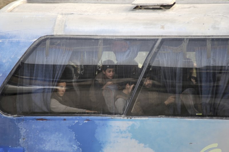 In this photo released on Thursday March, 22, 2108 by the Syrian official news agency SANA, shows rebel fighters and their families inside a bus that is evacuating them to Idlib province from Harasta in eastern Ghouta, a suburb of Damascus, Syria. Buses from the Syrian Ministry of Transport and Syrian Red Crescent vehicles were seen on the outskirts of Harasta on Thursday, after crossing the last Syrian Army checkpoint before the town. (SANA via AP)