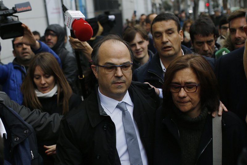 Catalan presidential candidate Jordi Turull, center, is surrounded by journalists as he leaves the Supreme Court with his wife Blanca Bragulat during a break for lunch in Madrid, Friday, March 23, 2018. A Spanish Supreme Court judge has charged 13 Catalan separatist politicians, including fugitive president Carles Puigdemont, with rebellion for their attempt to declare independence from Spain. Judge Pablo Llarena issued the indictment on Friday, wrapping a four-month long investigation into the events last fall. (AP Photo/Francisco Seco)