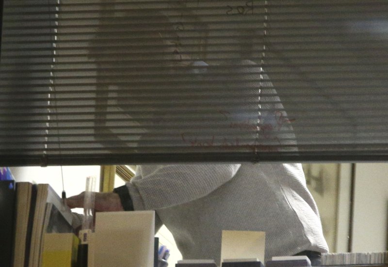 The scene at a window as Information Commissioner's Office enforcement officers work inside the offices of Cambridge Analytica in central London after a High Court judge granted a search warrant, Friday March 23, 2018. The investigation into alleged misuse of personal information continues Friday to determine whether Cambridge Analytica improperly used data from some 50 million Facebook users to target voters with ads and political messages. (Yui Mok/PA via AP)