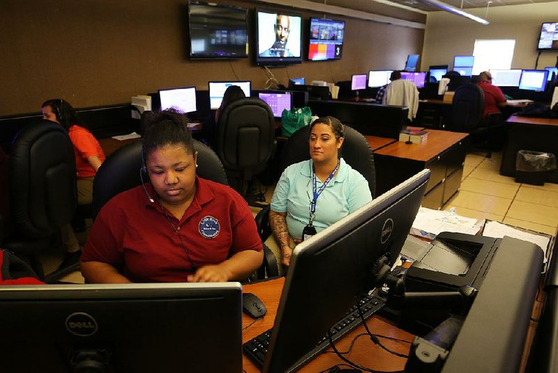 In this photo from March 16, 2017, Kendra Williams (left) trains new employee April Staggers at Little Rock’s 911 Communications Center. A year later, positions remain open and emergency calls aren’t always being answered as quickly as national standards require. 