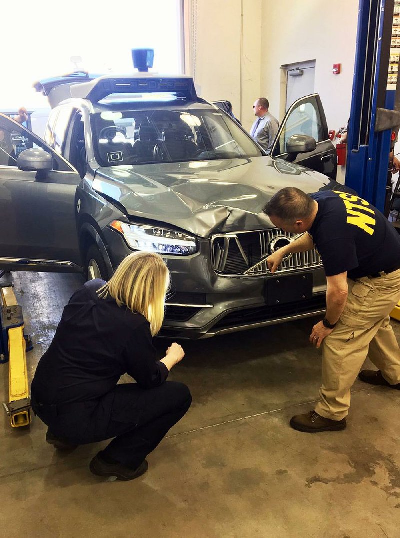 Investigators examine the self-driving Uber SUV that struck and killed a woman last week in Tempe, Ariz., in this photo provided by the National Transportation Safety Board.
