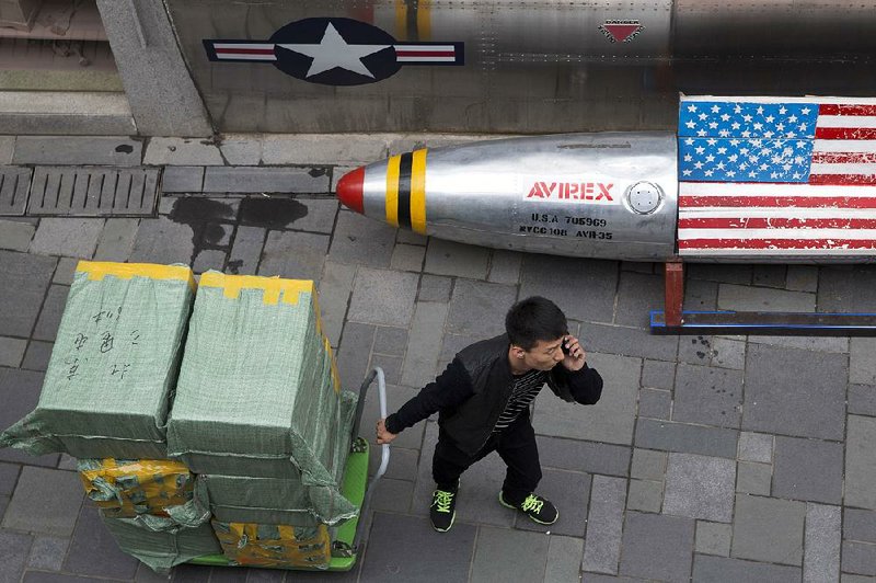 A deliveryman pulls a cart of goods past a U.S. apparel store Friday in Beijing. China announced Friday a list of U.S. goods that may be hit with higher tariffs in the trade dispute with the United States.