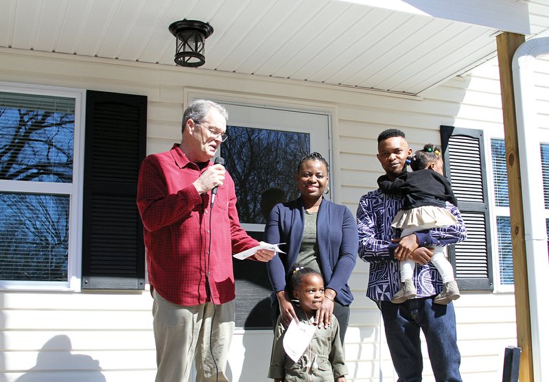 Jack Porter, Garland County Habitat for Humanity's board president, welcomes the Yamga family, Marie, Romeo and two daughters Joyce and Angela, on the porch of their new home on Cones Road during their home dedication on March 3, 2018. (The Sentinel-Record/Rebekah Hedges)