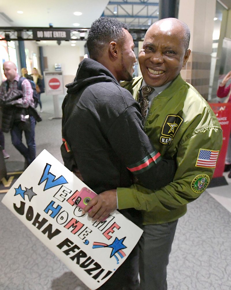 John Feruzi greets his uncle Watata Mwenda (right) Tuesday at the Northwest Arkansas Regional Airport in Highfill. Feruzi spent years in a refugee camp in Malawi after fleeing his native Republic of the Congo.