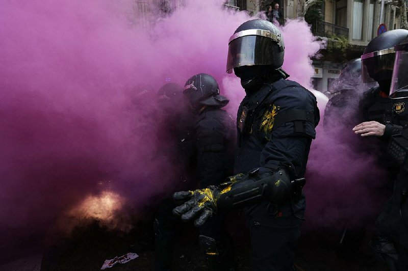 Catalan regional police officers stand amid smoke from a smoke bomb during clashes with independence supporters trying to reach the Spanish government office Sunday in Barcelona, Spain.