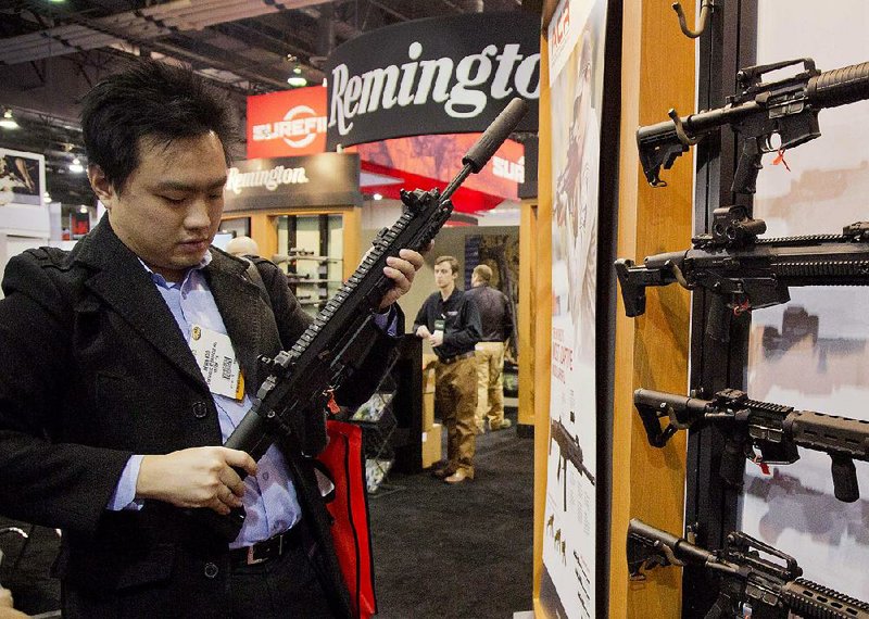 Accessories manufacturer Kevin Kao examines a military-grade Remington Adaptive Combat Rifle at the 35th annual Shooting, Hunting and Outdoor Trade Show in Las Vegas in 2013. The 200-year-old gun-making company filed for bankruptcy protection on Sunday.  
