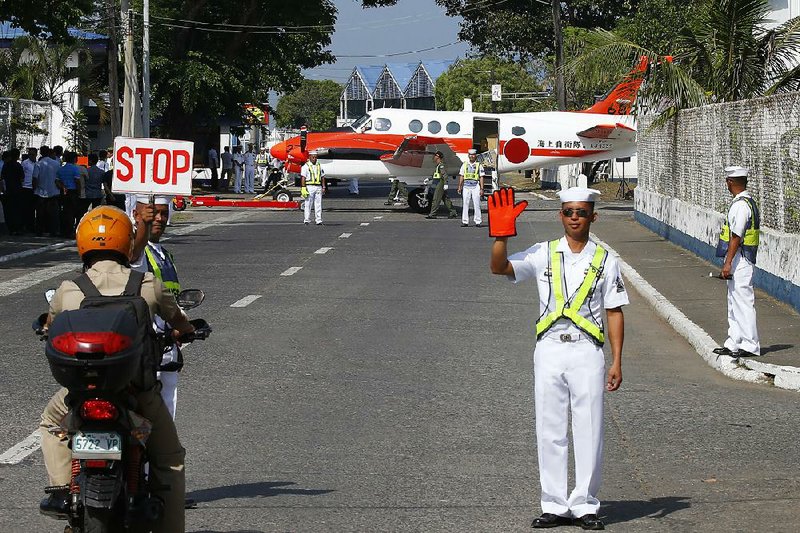 Traffic is briefly stopped as one of three Beechcraft TC-90 aircraft from the Japan Ministry of Defense is towed Monday across the road for a formal turnover to the Philippine navy at Naval Base Heracleto Alano in Sangley Point, south of Manila, Philippines.  
