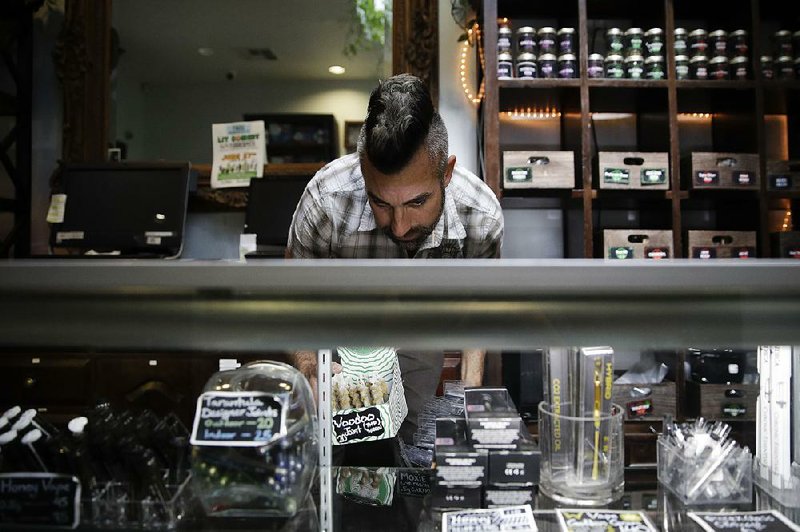 Jerred Kiloh, owner of the Higher Path medical marijuana dispensary, stocks shelves with cannabis products in Los Angeles in June. California regulators have warned the popular cannabis-shopguide website Weedmaps to take down ads from illegal sellers or face penalties.  