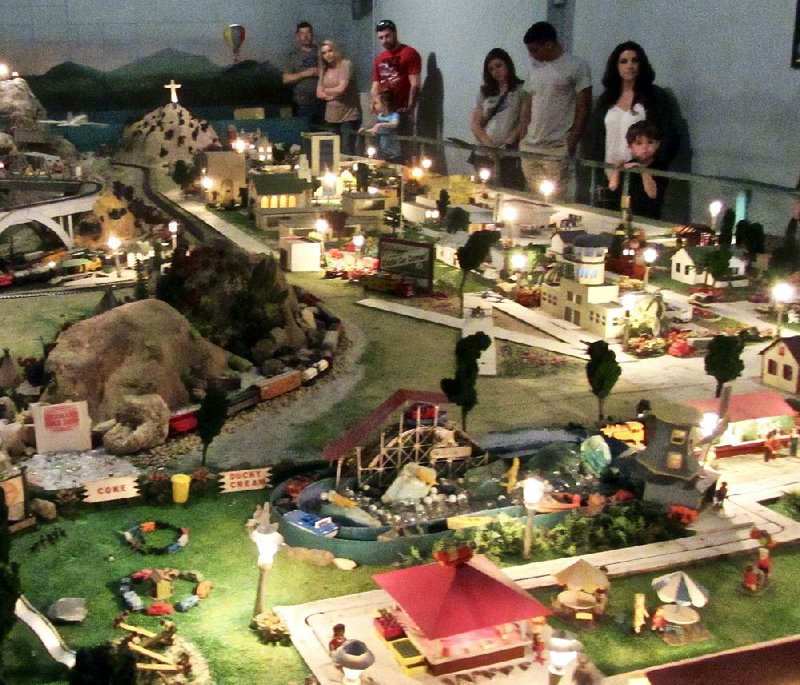 Visitors to Tiny Town in Hot Springs view a melange of landscapes traversed by model trains. A miniature copy of the Christ of the Ozarks statue can be seen. 