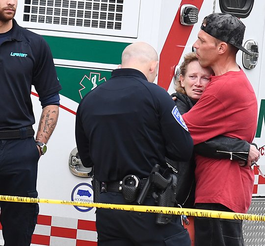 The Sentinel-Record/Grace Brown FIRE SCENE: A Hot Springs police officer speaks with a distraught woman as she is comforted by an unidentified man Tuesday evening following a fatal fire at Polo Run Apartments, 126 Manor Lane.
