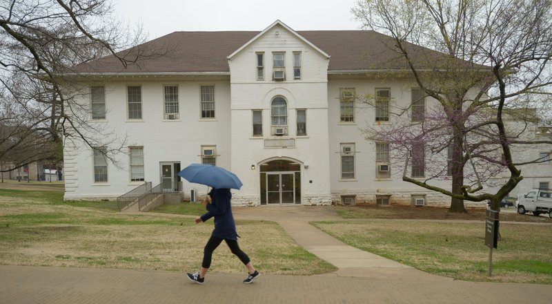 A student walks Wednesday past the School of Social Work on the University of Arkansas campus in Fayetteville. The university is seeking trustee approval for a $42.5 million Student Success Center planned for the building’s site north of Old Main. 