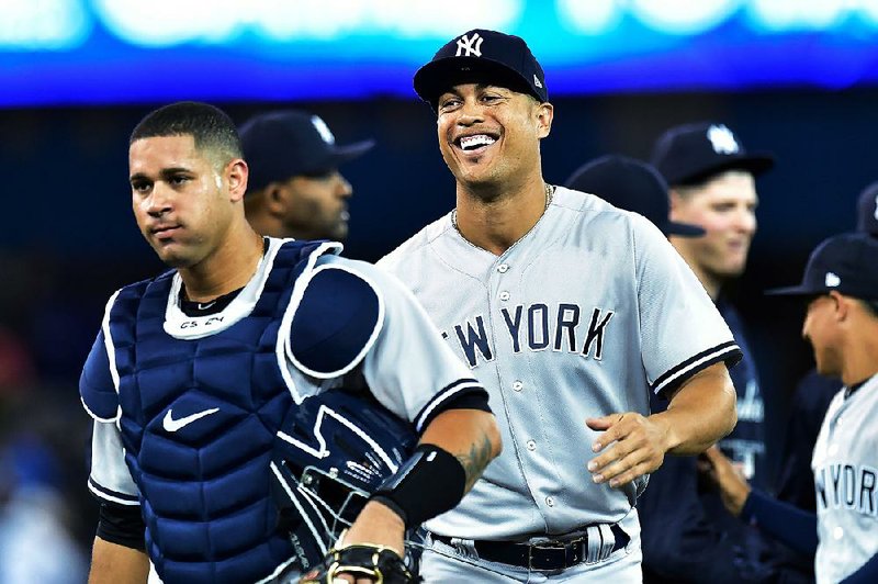 New York Yankees right fielder Giancarlo Stanton, right, and catcher Gary Sanchez, left, celebrate with teammates after defeating the Toronto Blue Jays in a baseball game in Toronto, Thursday, March 29, 2018. 