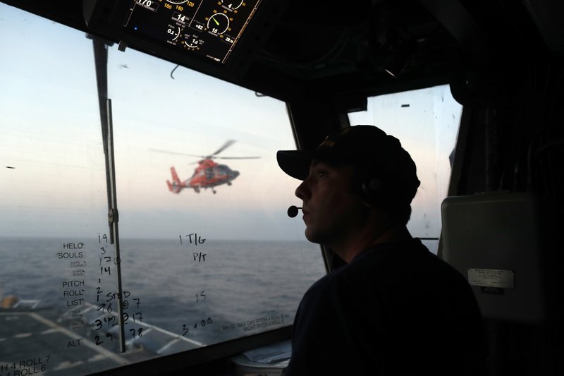 FILE - In this March 2, 2017 photo, an unidentified U.S. Coast Guardsman communicates with the pilot of a helicopter during take-off and landing exercises on the U.S. Coast Guard cutter Stratton in the eastern Pacific Ocean. The U.S. Coast Guard is teaming up with the Mexican and Colombian navies off South America's Pacific coast to go after seafaring smugglers, opening a new front in the drug war. (AP Photo/Dario Lopez-Mills, File)