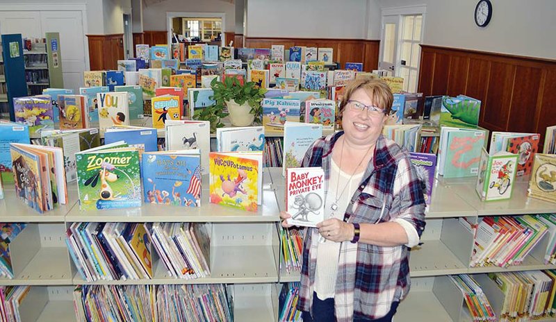 Kathy Gunter, children’s programming director for the Maumelle Library, holds one of her favorite children’s books as she stands in the remodeled children’s area, which has new furniture and a children’s programming room. The $1.945 million project includes five new study rooms and another meeting room, as well as 39 additional parking spaces.