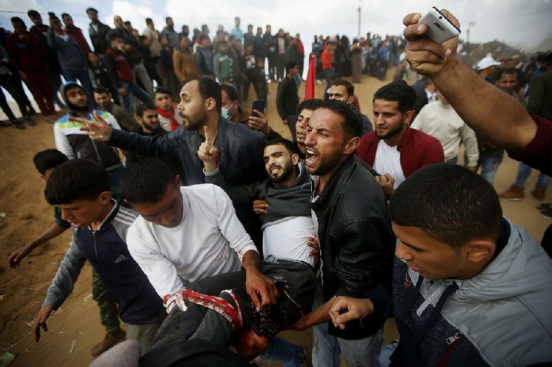Protesters carry away a wounded man during deadly clashes with Israeli troops along the Gaza Strip border, where thousands of Palestinians had gathered to demonstrate against the Israeli blockade. 
